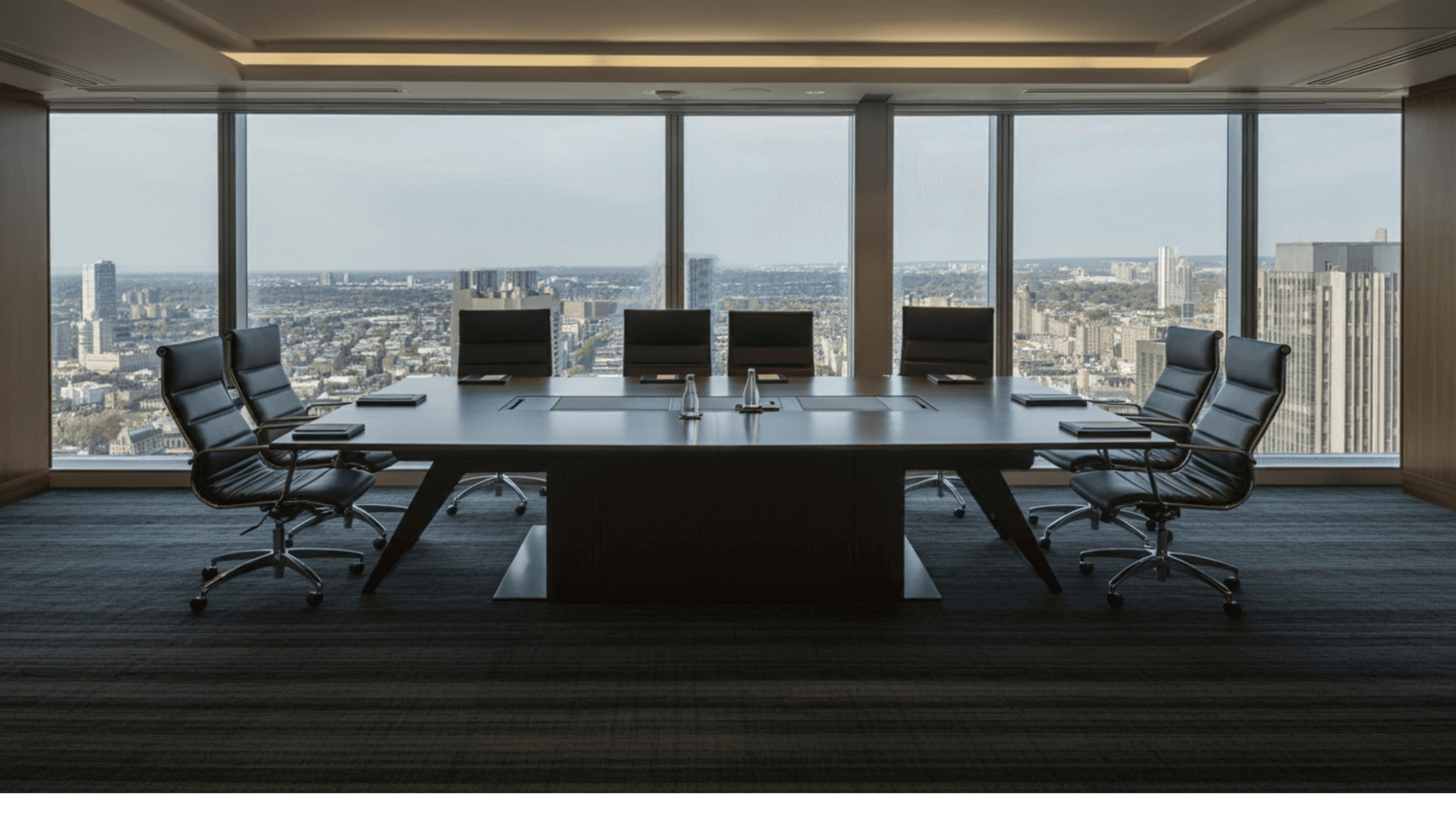 Empty boardroom overlooking a city skyline through floor-to-ceiling windows